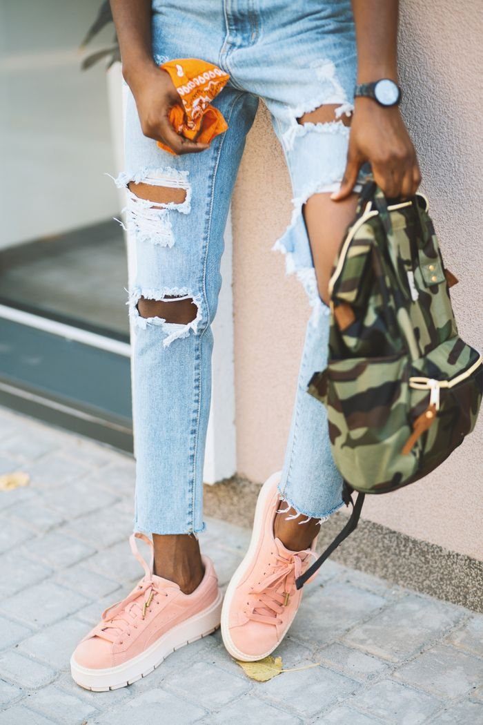 gallery-3 Fashionable young woman in ripped jeans and pink sneakers outdoors.