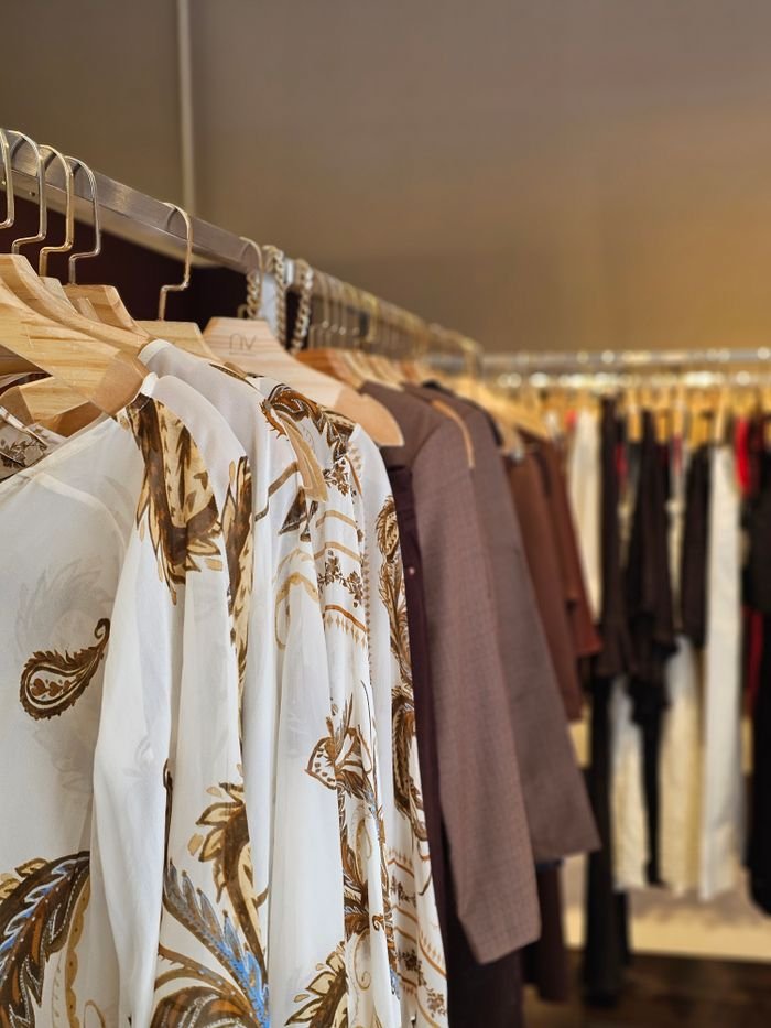 gallery-2 Stylish assortment of clothes hanging on racks in a fashionable boutique featuring elegant patterns.