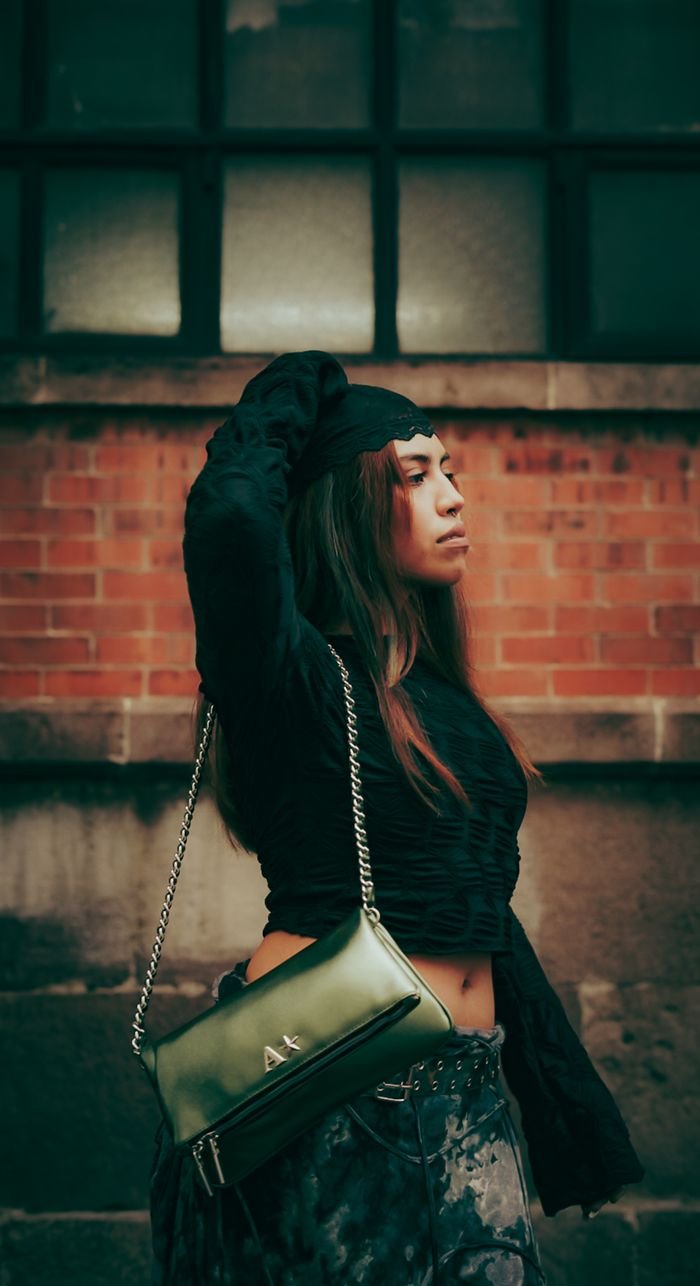 contact-img Fashionable woman posing against a brick wall, showcasing urban street style.