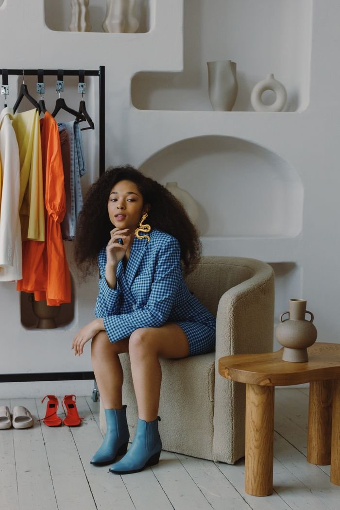 Mastering the First Impression: Your intriguing post title goes here Fashionable woman in blue blazer sitting on a chair in stylish interior with clothing rack.