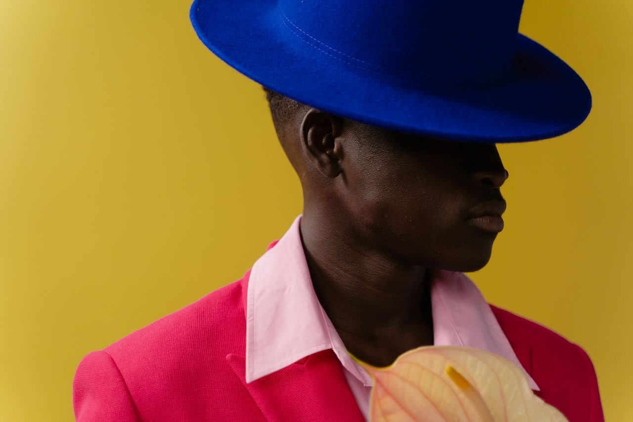 ours-journey Fashionable portrait of a man in a pink suit, blue hat, with a yellow background.