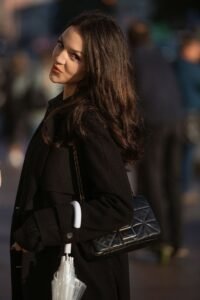 Belt Bag Guide: Best Styles, Sizes and How to Wear It in 2026 woman wearing a black leather belt bag across her chest while walking outdoors