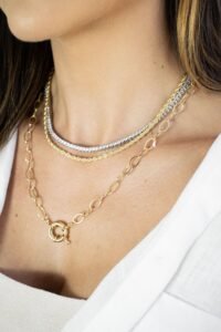 woman wearing three layered necklaces of different lengths against a white sweater