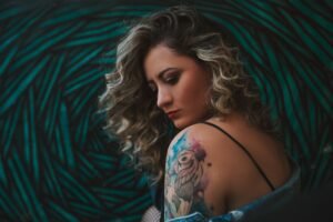 woman getting a fine line floral tattoo on her forearm in a tattoo studio