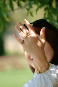 close up of a gold mom bracelet with three engraved birthstone charms on a woman's wrist