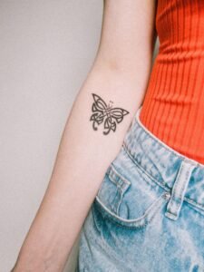 close up of a fine line butterfly tattoo on a woman's wrist