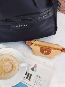 Belt Bag Guide: Best Styles, Sizes and How to Wear It in 2026 flat lay comparison of phone, wallet and keys next to a small belt bag showing size reference