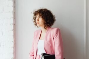A-Line Tops: The Ultimate Fit Guide for Every Body (2026) woman wearing a blush pink ballet wrap top with tailored trousers and a blazer in an office setting