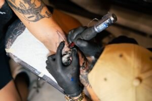 tattoo artist working on a fine line design on a client's forearm