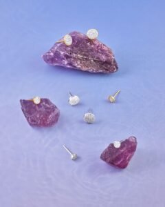 three pairs of sterling silver earrings, a stud, a small hoop and a huggie, on a neutral background