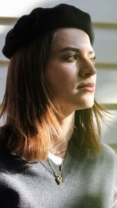 flat lay of a black wool Basque beret beside three other beret hat styles on a neutral background
