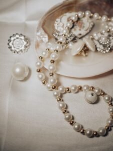 close up of gold drop pearl earrings against a cream sweater, daylight
