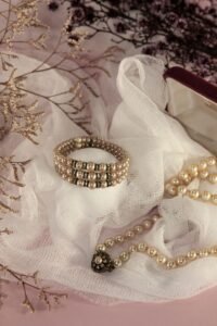 strand of cultured pearls beside a pearl bracelet on a linen cloth