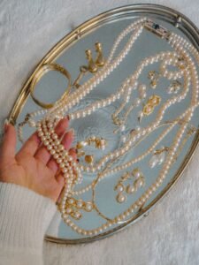 flat lay of gold pearl bracelet, gold and pearl ring, and drop pearl earrings on linen