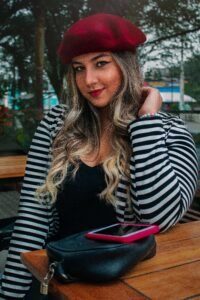 side by side photo of a wool beret, a felt trilby and a straw boater hat on a wooden table