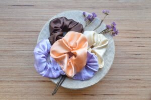 Hair Scrunchies 2026: The Ultimate Guide to Styles Flat lay of silk, satin and velvet hair scrunchies in black and neutral colors on a marble surface