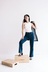 woman wearing a white high neck tank top with high rise jeans in natural daylight